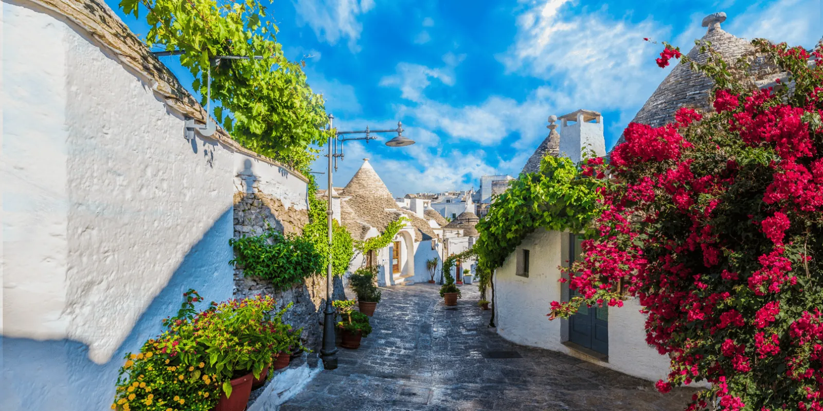 Flowers over a narrow Alberobello lane