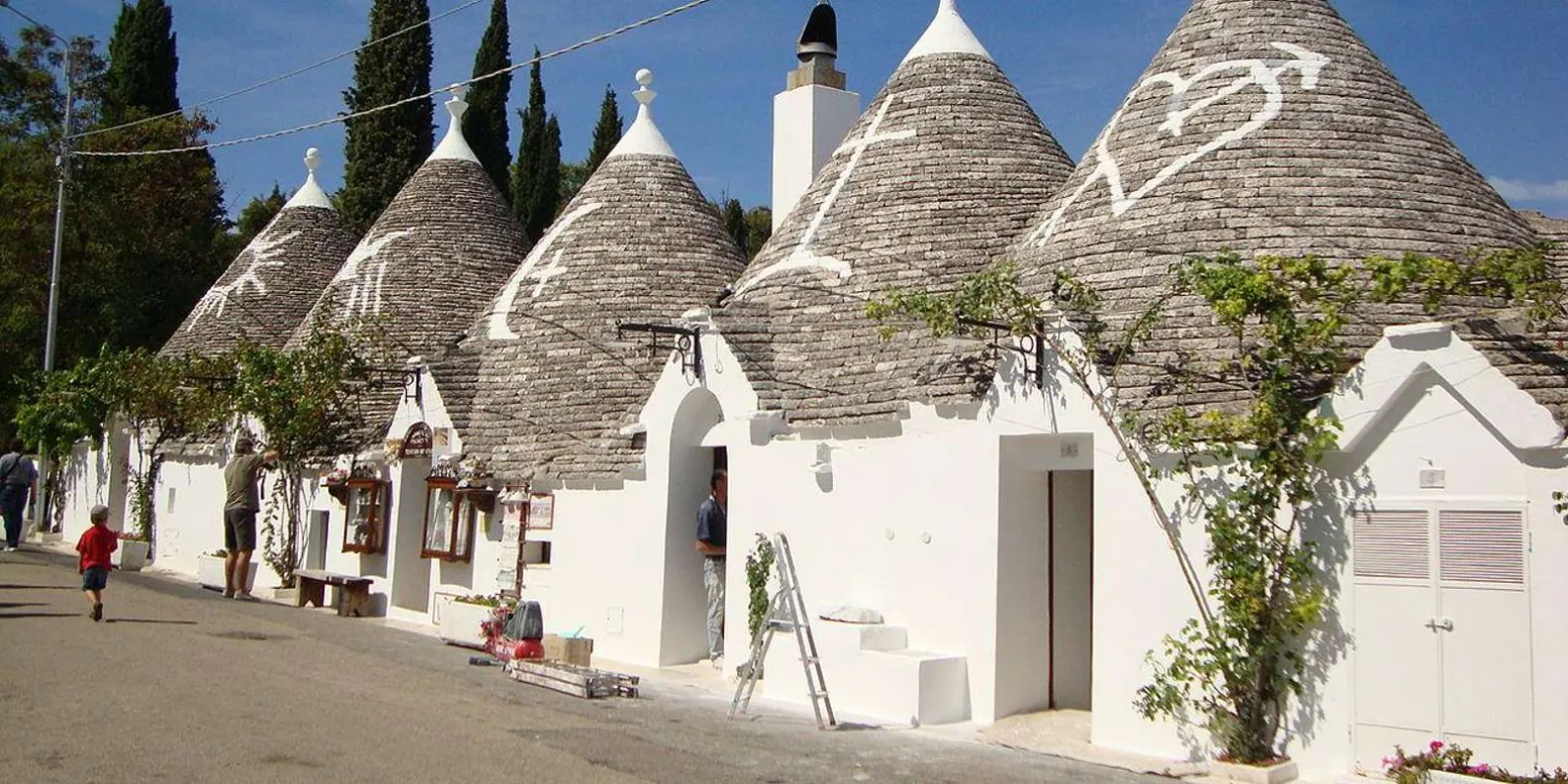 Trulli-lined street under a blue sky